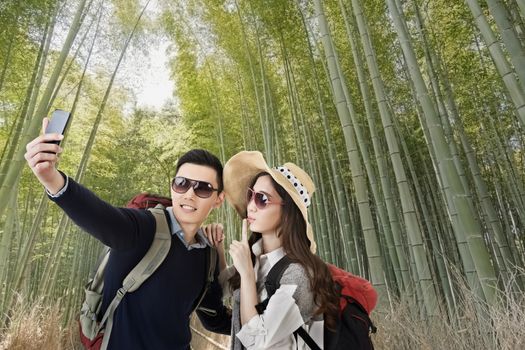 Asian couple travel and selfie in arashiyama bamboo forest, Kyoto, Japan.