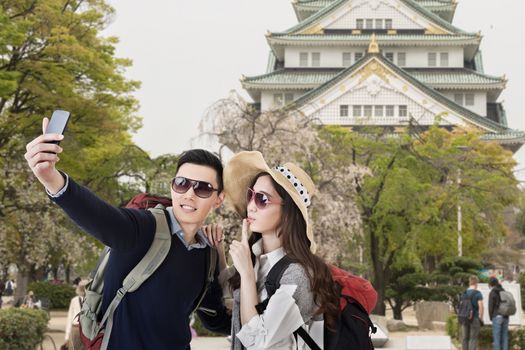 Asian couple travel and selfie in castle at Osaka, Japan.