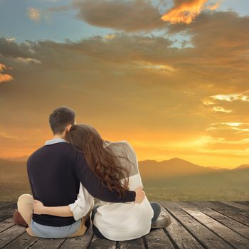 Asian young couple sit and hug together against the sky in outdoor.
