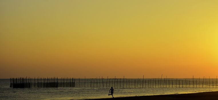 Runner over a fiery sunset beach