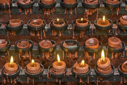 Lit and unlit red little candle offerings of people for their loved ones and prayer requests