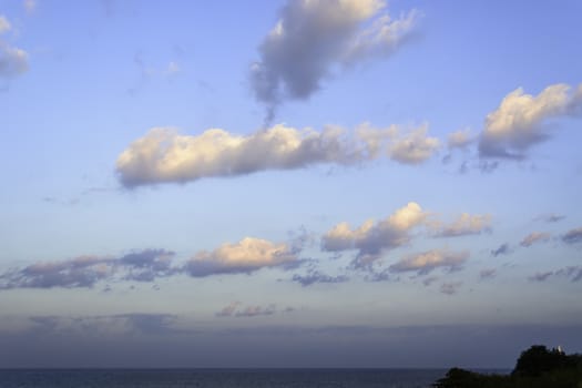 Tiny lighthouse and vast ocean during sunrise.