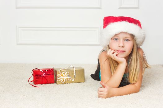 Girl in a Christmas cap lies outside the packed gifts