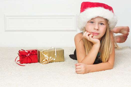 Girl in a Christmas cap lies outside the packed gifts