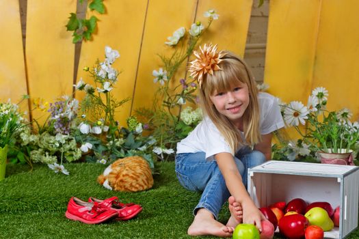 Little girl sitting on the grass near the fence