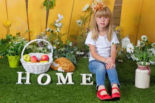 Little girl sitting on the grass near the fence