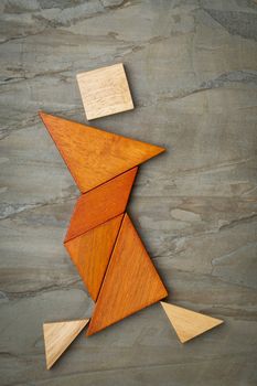 abstract figure of a female dancer built from seven tangram wooden pieces, a traditional Chinese puzzle game; slate rock background background, the artwork copyright by the photographer