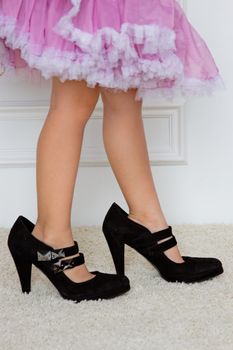 Baby foot in women's high-heeled shoes. close-up