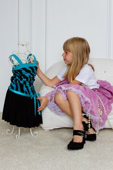 Girl in violet dress stands near mannequin in children store.