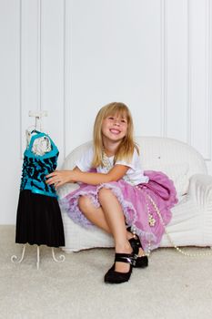 Girl in violet dress stands near mannequin in children store.