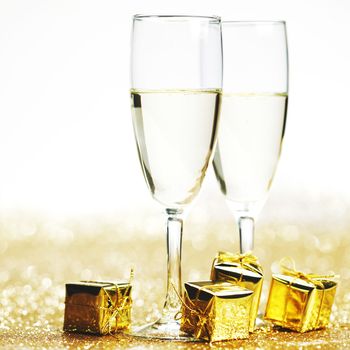 Champagne in glasses and gift box on golden background