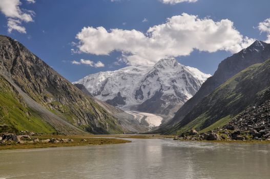 Picturesque view of green slopes and snow-covered peaks of Tian-Shan Mountains, Kyrgyzstan