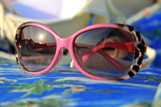 Womans sunglasses laying on the beach summertime