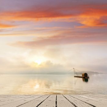 Morning concept with boat on lake with sunlight and dramatic sky, focus on wooden desk.