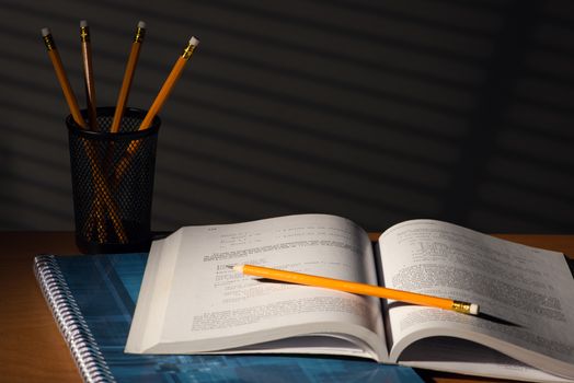 Desk with school book in night with light of blinds