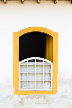 Decorative, colonial, yellow, vintage, window on a white wall in Paraty (or Parati), Brazil.