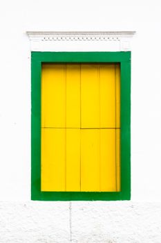 Decorative, colonial, green yellow, vintage, window on a white wall in Paraty (or Parati), Brazil.