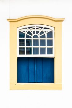 Decorative, colonial, beige, vintage, window on a white wall in Paraty (or Parati), Brazil.