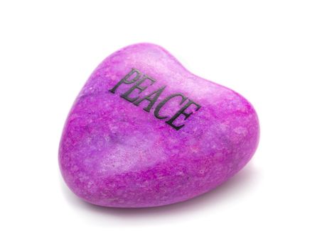 Close-up picture of a heart shaped stone with the word "Peace".