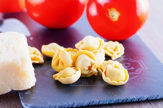 Agnolotti with cheese and tomatoes over black chopping board