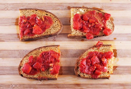 Bruschette with tomato and garlic over a wooden chopping board