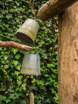 Two old rusty buckets hanging upside down from wooden pole