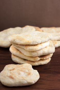 Homemade pita bread stacked on a wooden table.