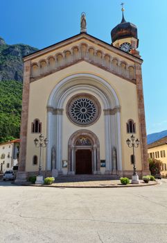 church in Mezzacorona village on sunny summer day with mountains in the background, Trentino, Italy