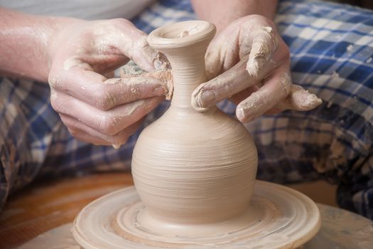 Hands of a potter, creating an earthen jar on the circle