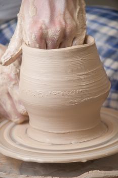 Hands of a potter, creating an earthen jar on the circle