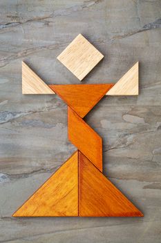 abstract figure of a female dancer built from seven tangram wooden pieces, a traditional Chinese puzzle game, slate rock background background, the artwork copyright by the photographer