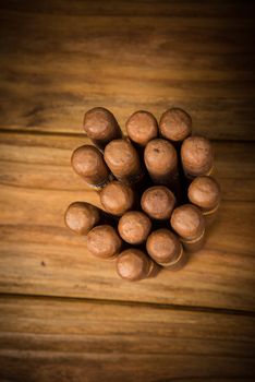 bunch of Cuban cigars on rustic wooden table in centre of background