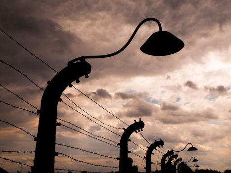 Lamp silhouette in concentration camp. It is part of barwire fence.