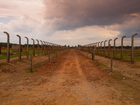 Muddy road between two barbwire fences in concentration camp