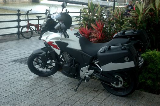 Singapore, Singapore - January 18, 2014: Honda motorcycle parked beside garden.