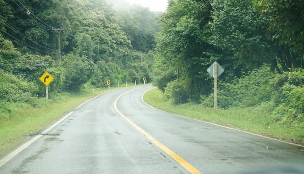 curve way of asphalt road through the green field.