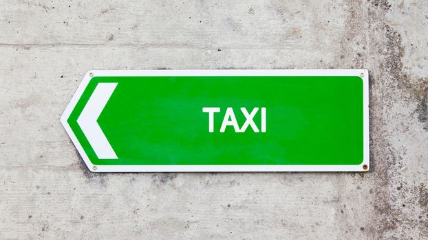 Green sign on a concrete wall - Taxi