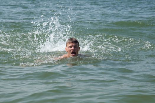 A swimming teen boy in the ocean