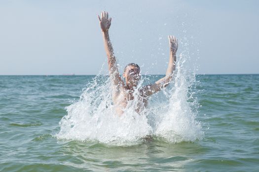 A teen boy making big splashes at the ocean