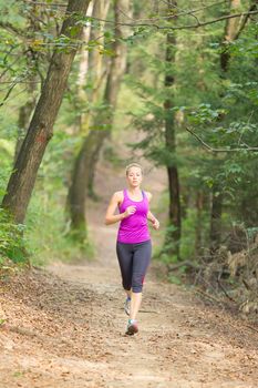 Pretty young girl runner in the forest.  Running woman. Female Runner Jogging during Outdoor Workout in a Nature. Beautiful fit Girl. Fitness model outdoors. Weight Loss. Healthy lifestyle. 