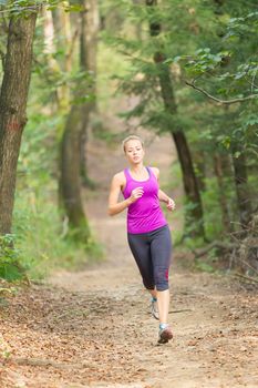 Pretty young girl runner in the forest.  Running woman. Female Runner Jogging during Outdoor Workout in a Nature. Beautiful fit Girl. Fitness model outdoors. Weight Loss. Healthy lifestyle. 