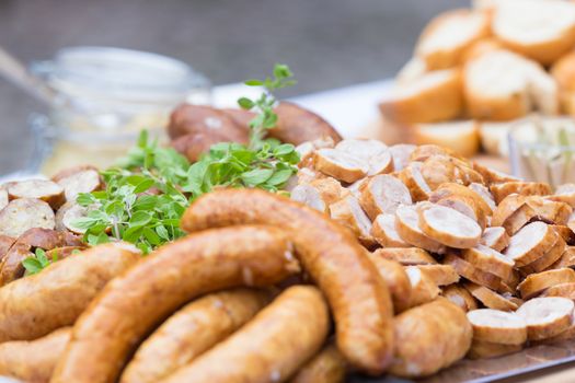 Dry sausage cold cuts. A variety of dry cold smoked meat products with herbs and mustard and  horseradish spreadon a wooden cutting board. 
