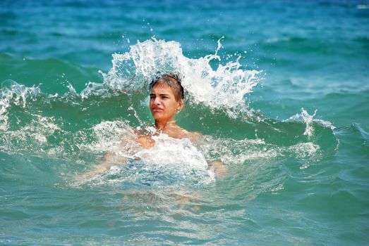 teenage boy swimming in sea water with wave