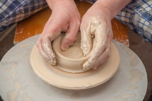 Hands of a potter, creating an earthen jar on the circle