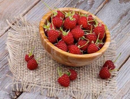 Perfect Ripe Raspberries with Stems in Wooden Bowl on Rustic Wooden background