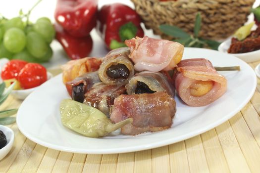 Tapas stuffed with prunes, figs, apricots and bacon on a light background
