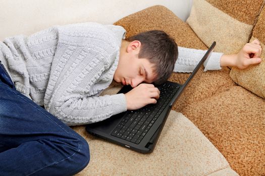 Tired Teenager falling asleep with Laptop on Sofa