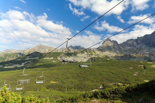 view on mountains in summer with ski lift on blue sky background