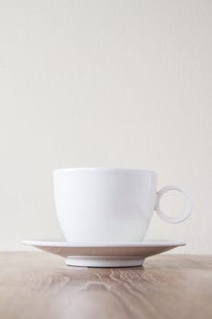 White cup of coffee on wooden table with copyspace area