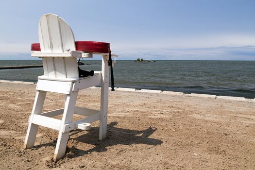Unmanned white lifeguard chair with floatation device on an empty beach. 